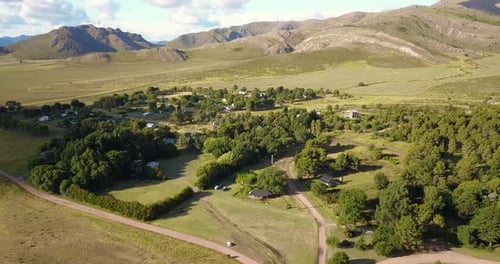 Aerial View Of Small Village With Green Foliage And Mountain Landscape Scenery. drone tilt-up