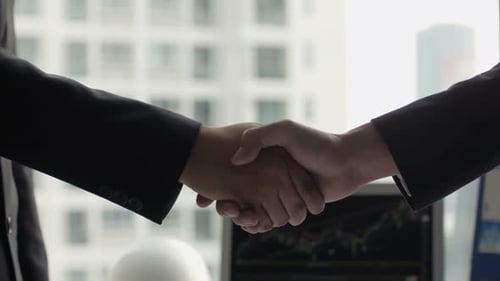 Businessmen Shake Hands in Office with Stock Chart