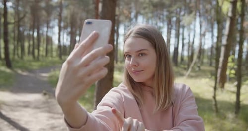 Young Attractive Smiling Woman Taking Selfies on a Smartphone in a Summer Forest