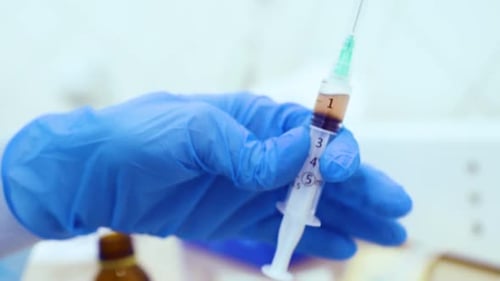 Le médecin tient dans sa main une seringue avec du plasma ou avec une injection en gros plan pour la régénération des cheveux et