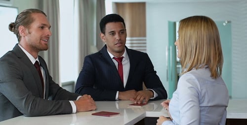 Businessmen Checking in at Hotel Reception Desk