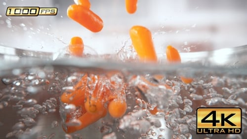 Vibrant Carrots Plunging into Bubbling Water in Slow Motion