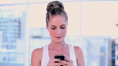 Smiling Woman Using a Smartphone Indoors