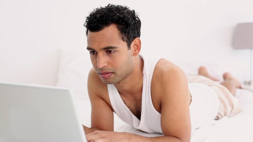 Man Lying in Bed Using Laptop Computer