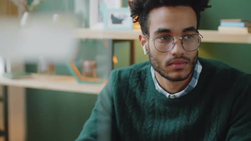 Pensive Male Office Worker Listening to Music with Wireless Earphones