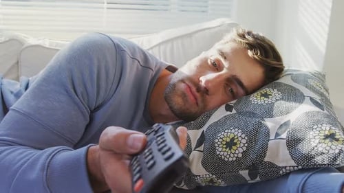 Young Man Lying on Sofa with Remote
