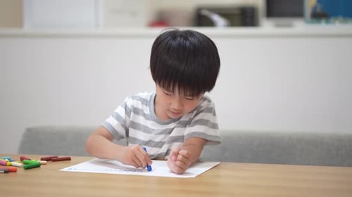 Young Child Drawing with Crayons at Table
