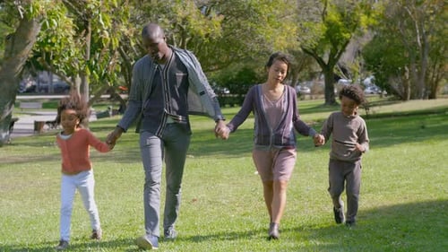 Happy Family Strolling Hand-in-Hand in Park