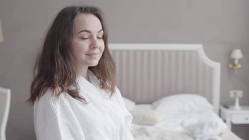 Smiling Woman in White Robe Relaxing in Bedroom