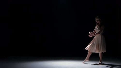 Woman Dances Ballet in Dark Studio