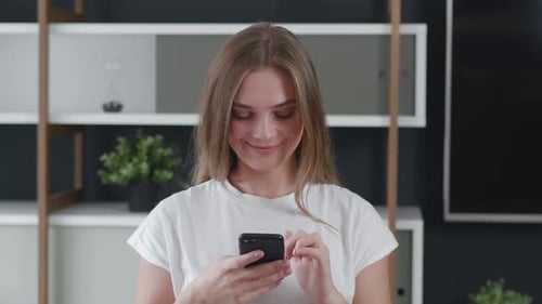 Beautiful Woman Using Smartphone Touching Screen Smiling at Modern Office Background. Browsing