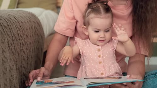 Mother Reading Picture Book with her Child at Home