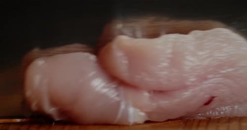 Rohes Hähnchenfilet wird in Stücke geschnitten.