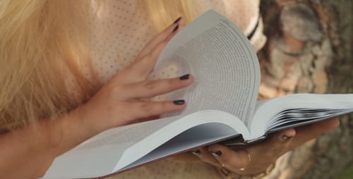 Woman Reading Book Outdoors on Sunny Day