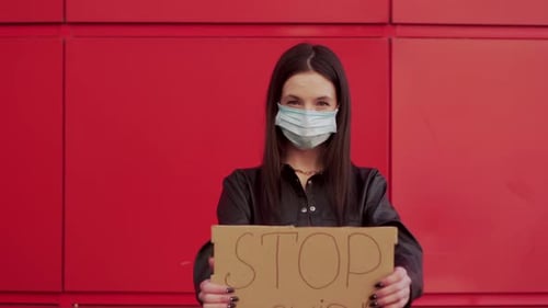 Young Woman Holds Stop Covid Sign in Urban Setting