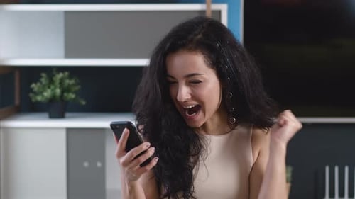 Excited woman reacts to good news on phone