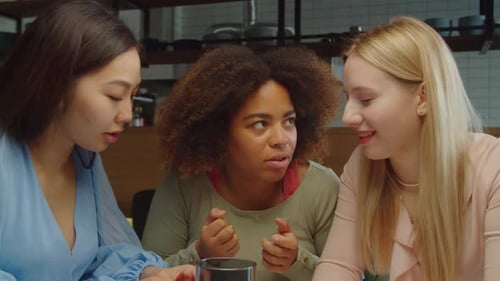 De joyeuses copines multiethniques chuchotent des ragots au café