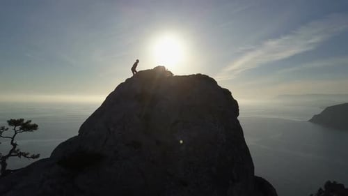 Flight Over of Young Woman Standing on the Top of a Mountain Facing the Sea