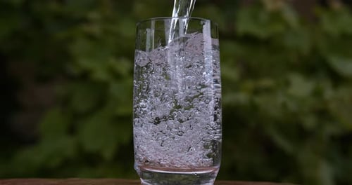 Pouring Clear Water into Glass Outdoors