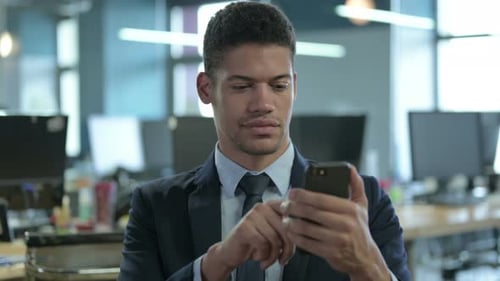 Young Adult Man Uses Smartphone in Modern Office