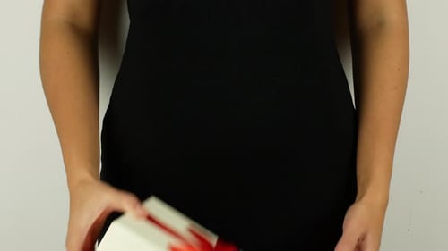 A woman in a black dress holds a gift in her hands. 4K video close-up of a Christmas present