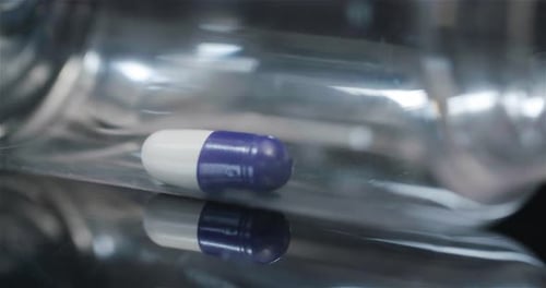 Einzelne medizinische Pille in kleiner Flasche, rotierend auf schwarzem Hintergrund