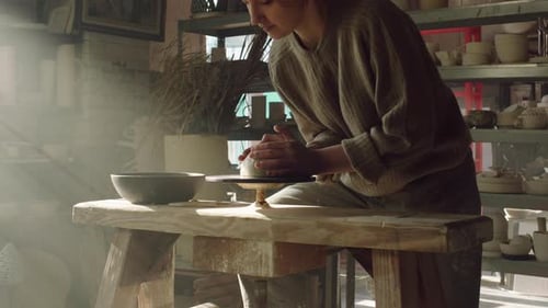Young Artist Shaping Clay on Pottery Wheel in Studio