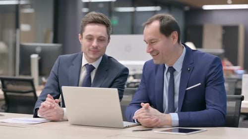 Businessmen Collaborating on Laptop in Modern Office