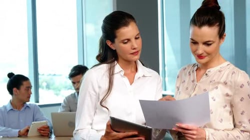 Two Women Reviewing Documents in Modern Office