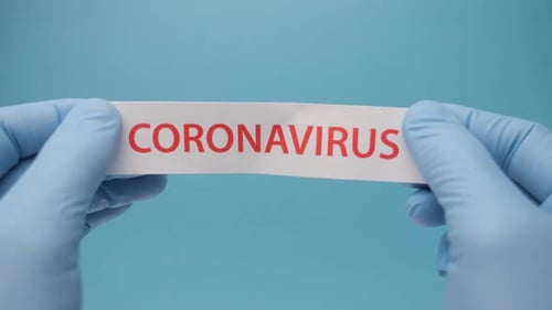 Hands in Gloves Tear Coronavirus Paper