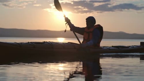 Kayaker Paddling Across Calm Water at Sunset