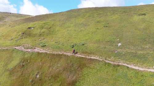 Aerial View of a Traveler with Backpack Climbing Along Mountain Slope. Epic Shot