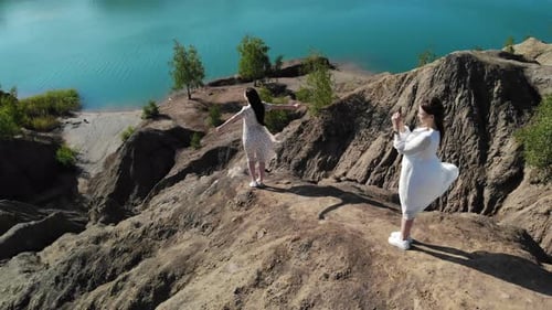 Two Beautiful Women in White Dresses are Photographed at the Top of the Mountain