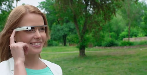 Smiling Woman Interacts with Smart Glasses in Urban Park