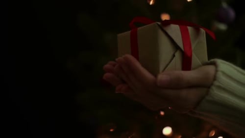 Hands Offering Christmas Gift with Warm Lighting