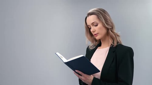 Blonde woman reading and writing in notebook