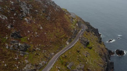 High Angle View of Car Passing Curve and Narrow Road High Above Sea Coast