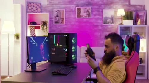 Gamer Using Computer at Desk in Purple Lit Room