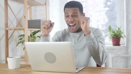 Man Celebrating Success While Working on Laptop