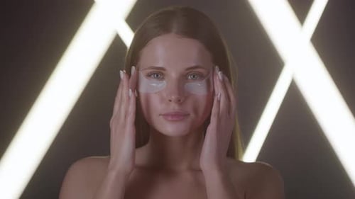 Woman Massaging Her Face with Eye Patches On