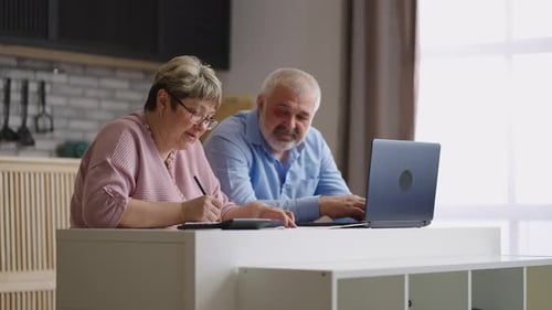 Mature Couple Working on Laptop at Kitchen Island