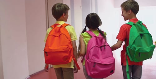 Children Walking Down School Hallway with Backpacks