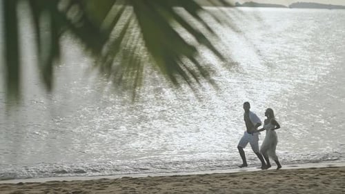 Couple Running Along Beach and Holding Hands