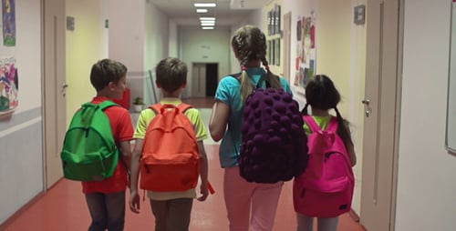 Children with Backpacks Walk Down School Hallway