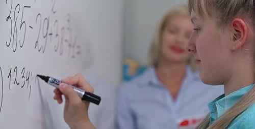 Student Works Math Problems on Whiteboard