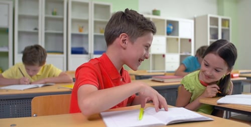 Elementary School Students Writing at Desks in Classroom