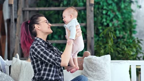 Mother Holds Baby Upward in Home Setting