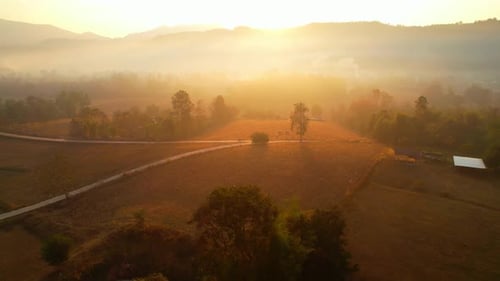 Aerial view over villages and barren fields in countryside during sunrise