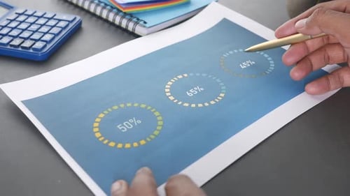 Mão de homem com caneta analisando gráfico de barras no papel