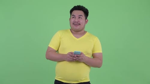 Man in Yellow T-Shirt Using Phone Thinking